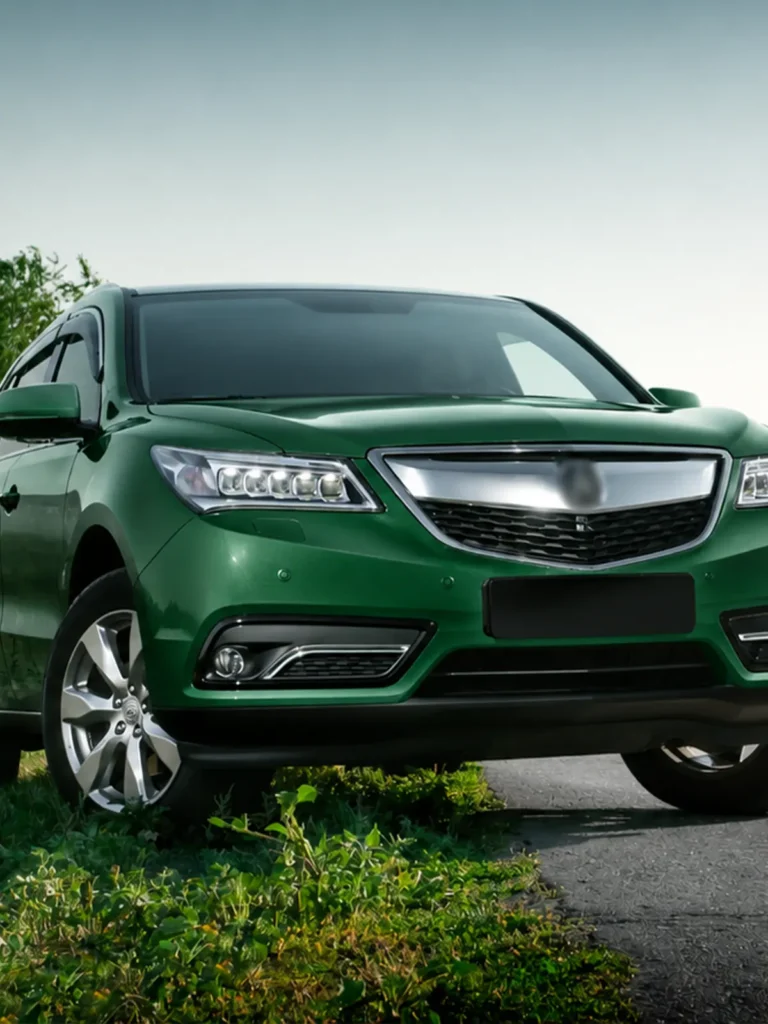 Front view of a green SUV with chrome grille and LED headlights, parked outdoors on a sunny day.